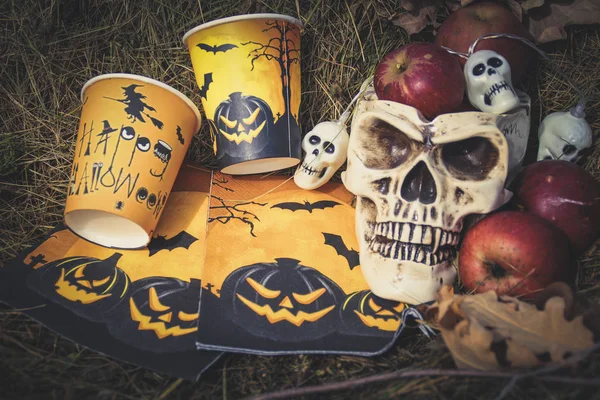 Halloween soon Autumn composition with halloween decorations. Skull,paper glass, garland, pumpkin. Straw backgtound.