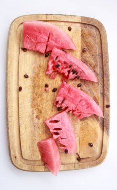Pembe karpuz kahverengi tohumları ile ahşap tahta üzerinde. Beyaz arka plan.