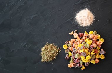 Pembe Himalaya tuz ve Provence otlar ile renkli İtalyan makarna düzeni. Makarna ve siyah koyu arka plan.