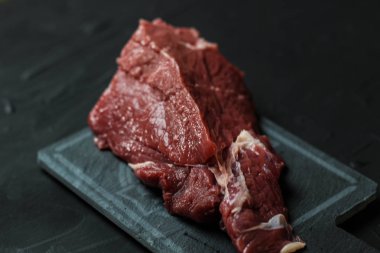 Kırmızı çiğ Dana eti üzerinde gri Seramik yağmur. Lezzetli yemekler için yemek tarifleri karanlık bir arka plan üzerinde.