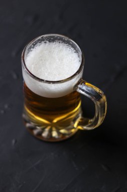 Karanlık bir arka plan üzerinde beyaz kabarık köpükle Light bira