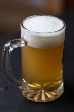 Karanlık bir arka plan üzerinde beyaz kabarık köpükle Light bira