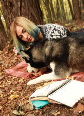 Siberian dış yapraklar bir dinlenme onun metresi ile sonbahar ormanda yaşıyor. Kız bir şapka örme kazak bir kitap okur ve tozluk ile etek. Siyah ve beyaz köpek ve tüylü yaprakları.