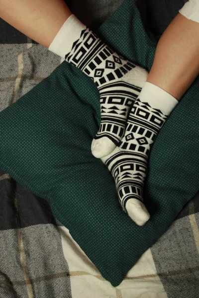 妇女的腿在美丽的袜子与黑色几何正宗装饰品 腿躺在绿色枕头上 — 图库照片