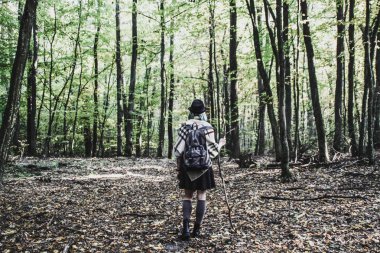 Mavi biter örme etnik pançolar, etek ve bir sırt çantası ile sarışın kız. Atmosferini ısınma, sıcak ve güneş var. Ormanda Portret. Doğal arka plan. Kadın seyahat fotoğraf seyahat.