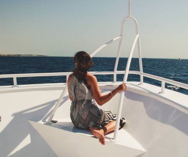 Geometrik bir şerit siyah beyaz elbiseli kız. Çözünmüş saç. Mısır'daki Kızıl Deniz gemide yolculuk. Esmer gezisinde. Moda fotoğraf çekimi.