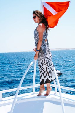 Geometrik bir şerit siyah beyaz elbiseli kız. Çözünmüş saç. Mısır'daki Kızıl Deniz gemide yolculuk. Esmer gezisinde. Moda fotoğraf çekimi.
