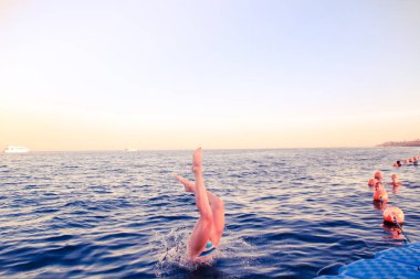 Mavi bikinili kız suya dalıyor. Mısır'daki red Sea'deki/daki sıçrama. Kızıl saçlı kadın atlamadan sonra su sıçramalarına