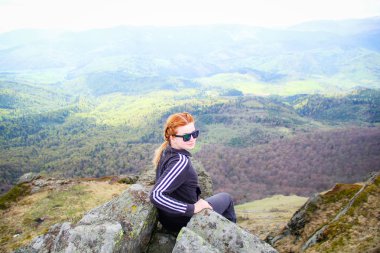Kız dağ manzaralı bir uçurumun kenarında oturur. Ukraynalı Karpat Dağları. Seyahat