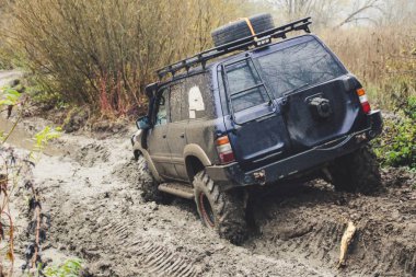Offroad araba büyük bataklıklar ile çalışır. Shrazjuk yağmur sonra. Zor yol. Kanlı kirli tekerlekler.