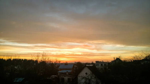 Sunset from the window. Orange clouds. City Silhouette.