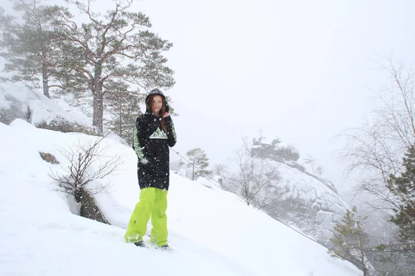 Kış orman. Bir kayaya kızdır. Siyah uzun sıska Kayak yeşil pantolon. Düşen kar Dovbush kayalar, Ukrayna