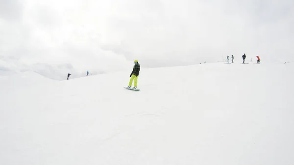 一个女孩在山上骑滑雪板 大量的雪 喀尔巴泰人滑雪夹克和裤子 — 图库照片