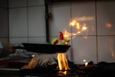 Pişirme Şef ve bir tavada bir alev çıkartıyor. Ateşle yemek. C