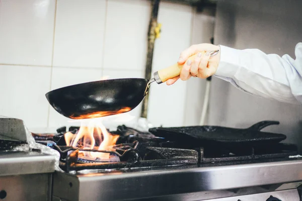 The chef cooking and makes a fire in a pan. Cooking with fire. C