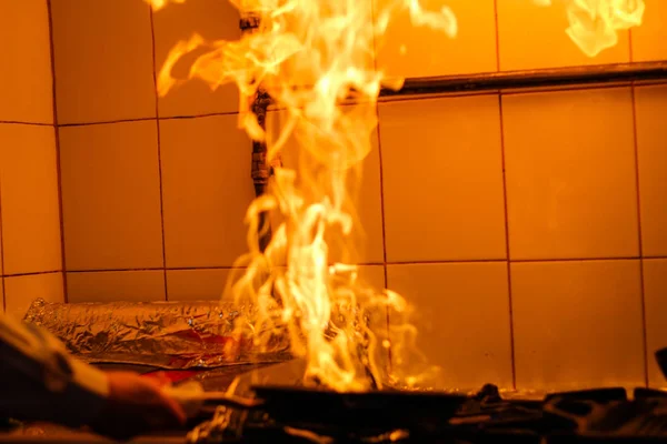 El chef cocina y hace un fuego en una sartén. Cocinar con fuego. C —  Fotos de Stock