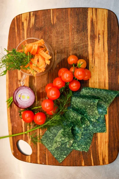 Köchin schneidet Gemüse. Tomaten, Petersilie, Zwiebeln, Äpfel. w — Stockfoto