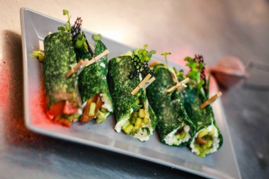 Kız şefi fesleğen peyniri ile yeşil krep rolleri hazırlanıyor