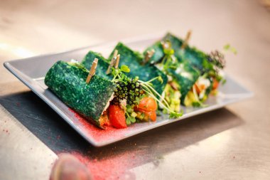 Kız şefi fesleğen peyniri ile yeşil krep rolleri hazırlanıyor