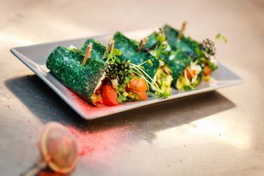 Kız şefi fesleğen peyniri ile yeşil krep rolleri hazırlanıyor