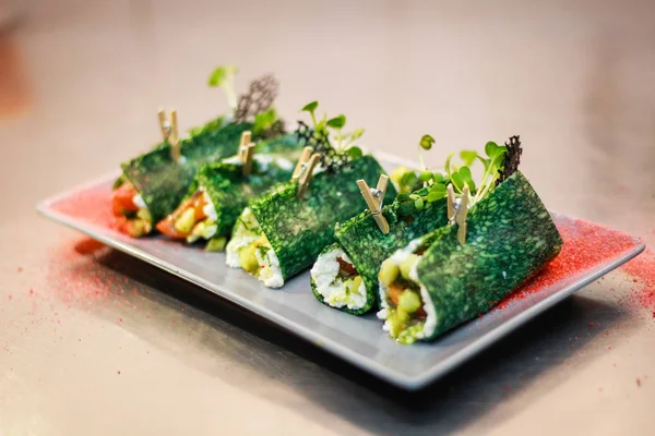 The girl's chef is preparing green crepe roles with basil cheese — Stock Photo, Image