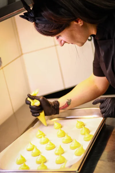 Кухарка дівчини готує еклектичний тістечко. Жовтий колір — стокове фото