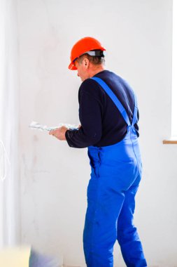 Elinde bir tükürme ile elinde turuncu bir inşaat fincan bir inşaatçı