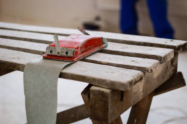 Elinde sandpap olan turuncu bina maskesi giymiş bir inşaatçı.