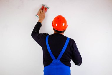 Elinde sandpap olan turuncu bina maskesi giymiş bir inşaatçı.