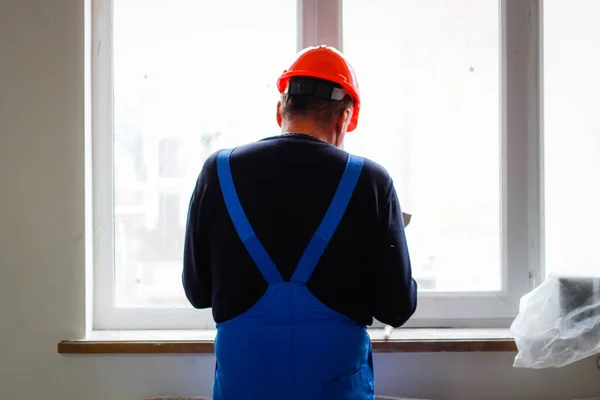 A builder in an orange construction cup in his hands with a spat