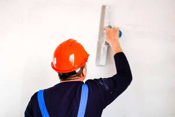 A builder in an orange construction cup in his hands with a spat