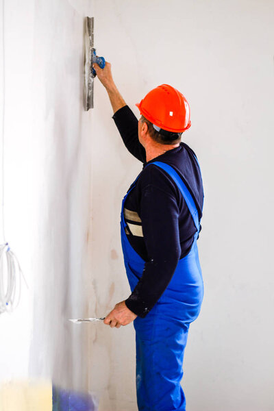 A builder in an orange construction cup in his hands with a spat