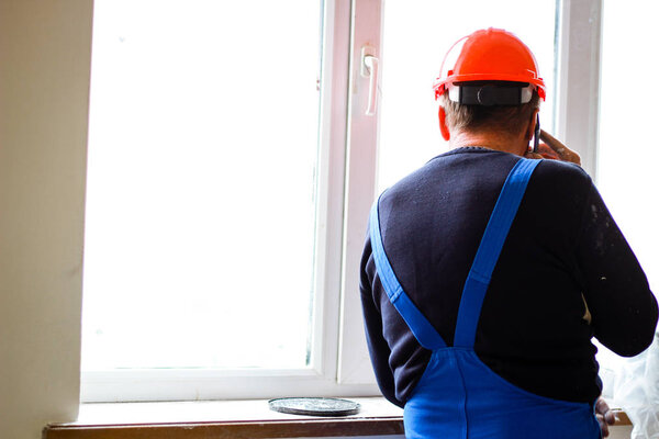 A builder in an orange construction cup in his hands with a spat