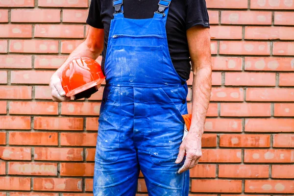 A builder with a construction cup in his hands against the backg