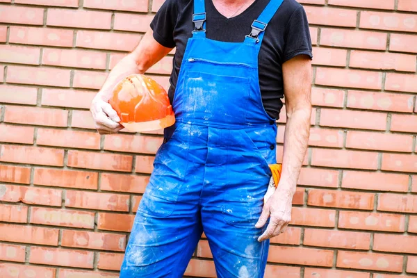 A builder with a construction cup in his hands against the backg