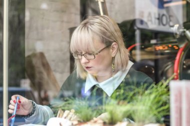 Kalın sarışın bir kadın bir kafede çalışıyor. Bir iş kadını yazıyor 