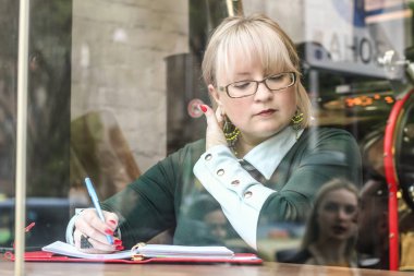Kalın sarışın bir kadın bir kafede çalışıyor. Bir iş kadını yazıyor 