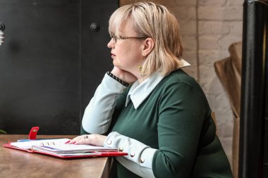 Kalın sarışın bir kadın bir kafede çalışıyor. Bir iş kadını yazıyor 