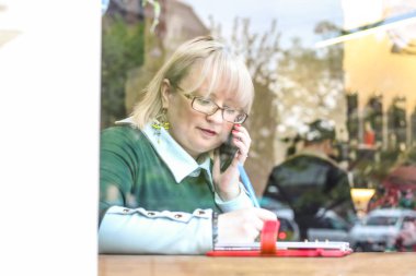 Kalın sarışın bir kadın bir kafede çalışıyor. Bir iş kadını yazıyor 