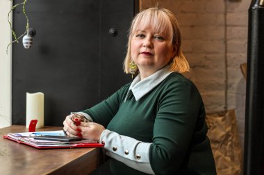 Kalın sarışın bir kadın bir kafede çalışıyor. Bir iş kadını yazıyor 