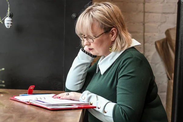 Kalın sarışın bir kadın bir kafede çalışıyor. Bir iş kadını yazıyor 