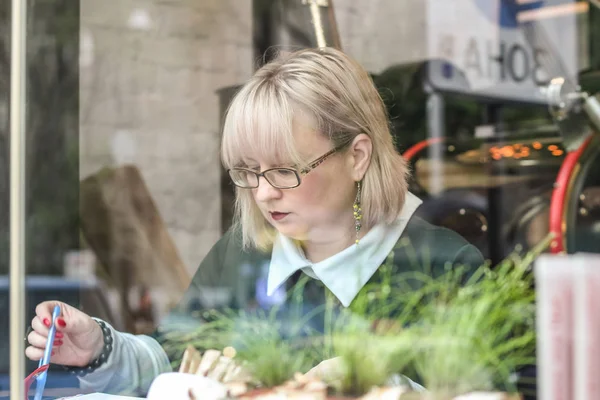 Kalın sarışın bir kadın bir kafede çalışıyor. Bir iş kadını yazıyor 