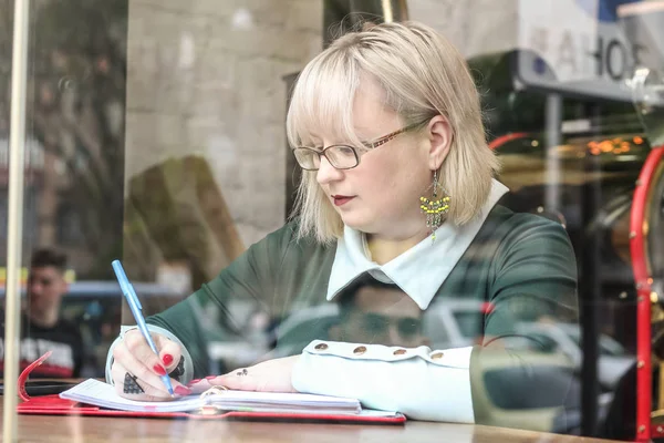 Kalın sarışın bir kadın bir kafede çalışıyor. Bir iş kadını yazıyor 