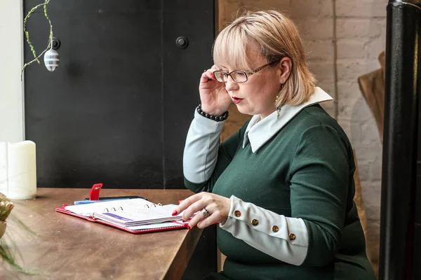 Kalın sarışın bir kadın bir kafede çalışıyor. Bir iş kadını yazıyor 