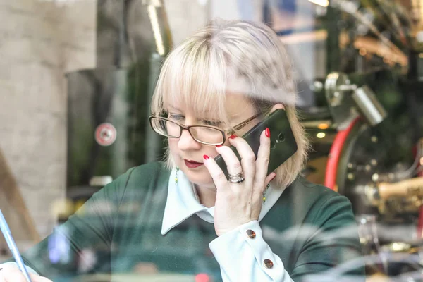 Kalın sarışın bir kadın bir kafede çalışıyor. Bir iş kadını yazıyor 