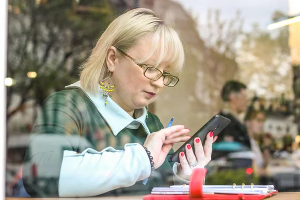 Kalın sarışın bir kadın bir kafede çalışıyor. Bir iş kadını yazıyor 