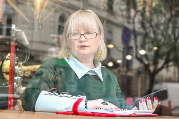 Kalın sarışın bir kadın bir kafede çalışıyor. Bir iş kadını yazıyor 