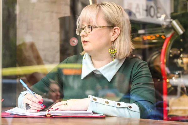 Kalın sarışın bir kadın bir kafede çalışıyor. Bir iş kadını yazıyor 