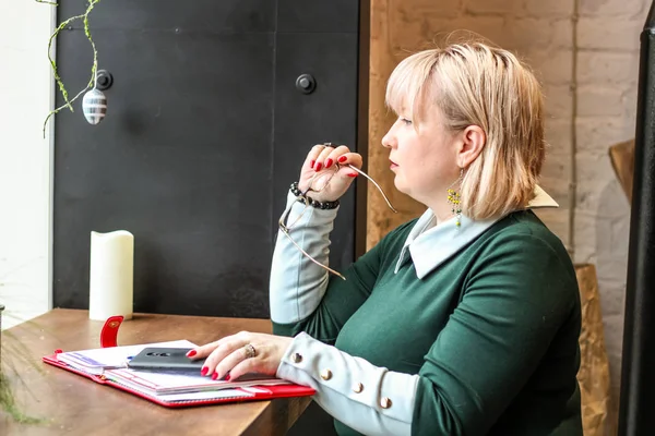 Kalın sarışın bir kadın bir kafede çalışıyor. Bir iş kadını yazıyor 