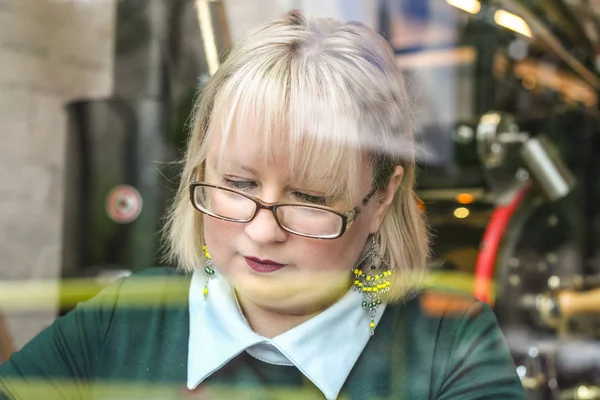 Kalın sarışın bir kadın bir kafede çalışıyor. Bir iş kadını yazıyor 